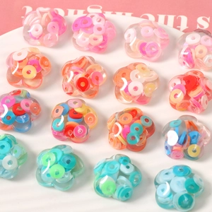 Transparent flower-shaped resin DIY charms filled with colorful clay flakes in a white tray