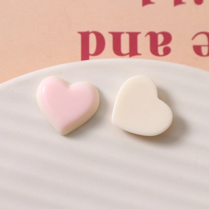 Makroaufnahme von rosa und cremefarbenen Harzherzen für DIY-Schmuck auf einem Teller