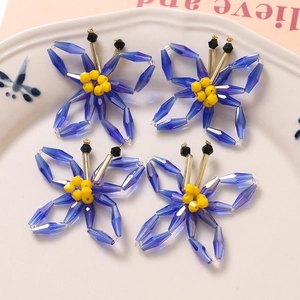 Detailed view of DIY Klein blue acrylic woven butterfly charms on a white ceramic plate