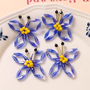 Macro shot of four blue acrylic butterfly beads with yellow centers in a white lace tray