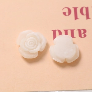 Macro detail of white resin rose charms with 3D embossed petals for DIY jewelry making