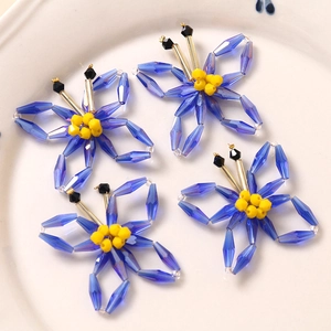 Set of four blue acrylic woven butterfly charms with yellow beads in a white ceramic dish