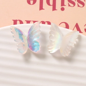 Dettaglio macro di ciondoli a farfalla in resina iridescenti e bianco latte per gioielli