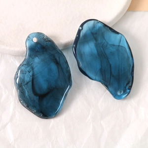 Macro detail of blue ink-wash resin pendants with irregular geometry and pre-drilled holes