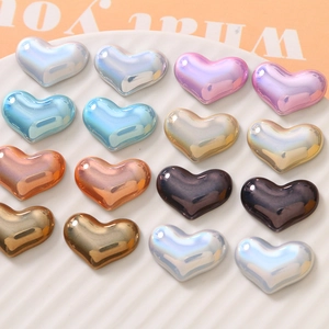 Pearlescent heart charms for DIY jewelry on white ceramic tray in assorted colors