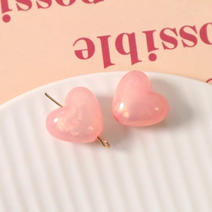 Detail von Herz-Harzperlen mit rosa Glitzer und Goldnadeln für DIY-Schmuckherstellung