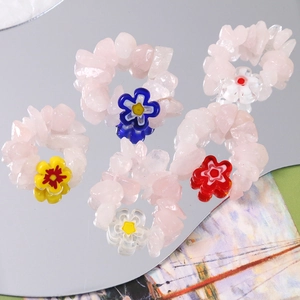 Handmade pink quartz bead rings featuring colorful glass floral centers on mirror surface