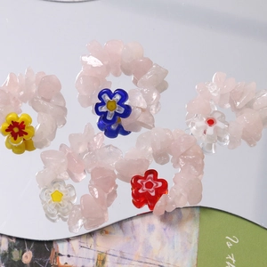Detail of five handmade rings with pink quartz chips and colorful glass flower charms