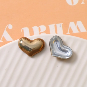 Macro shot of heart-shaped polished metal charms in gold and silver for jewelry making