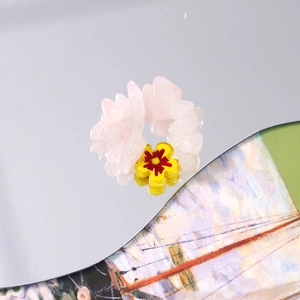 Macro shot of handmade beaded ring with pink quartz chips and yellow flower charm detail