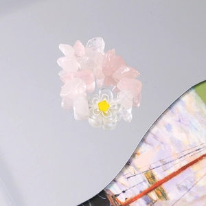 Detail view of handmade pink natural stone elastic ring with a white floral charm