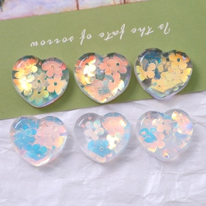 Macro shot of heart-shaped resin charms with holographic floral sequins for DIY crafts