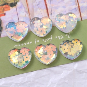 Detailed macro view of six transparent resin heart charms with iridescent floral sequins