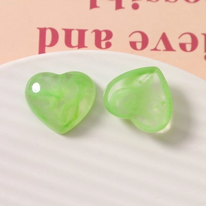 Close-up of green marble pattern heart-shaped resin charms on a white ceramic plate