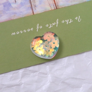 Macro shot of iridescent heart-shaped resin charm with orange flower patterns for DIY crafts