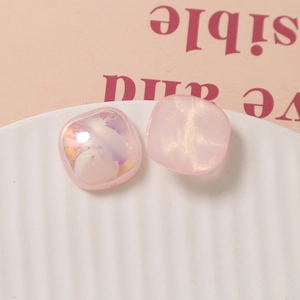 Close-up of pink iridescent square resin charms with pearl sheen for DIY jewelry making