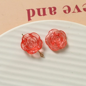 Détail d'une breloque rose en résine rouge translucide avec anneau en métal doré pour DIY