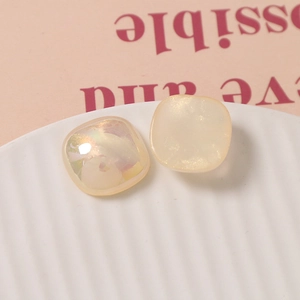 Detailed view of 18mm iridescent square resin charms with pearl sheen on ceramic plate