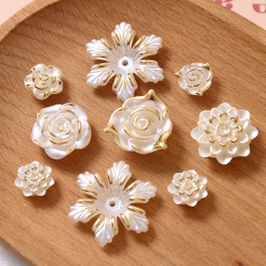 Détail de charmes de fleurs en résine blanche avec bordure dorée sur un plateau