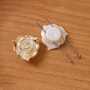 Détail de roses en résine blanche aux bords dorés avec tiges métalliques pour bijoux