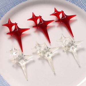 Close-up of red and clear resin four-point star DIY charms on a white ceramic plate