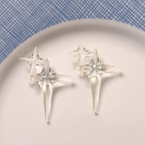 Close-up of transparent resin four-pointed star earrings on a white porcelain plate
