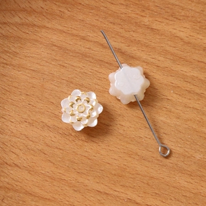 Détail macro d'une perle fleur en nacre avec bord doré et trou pour bijoux DIY