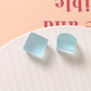 Vue macro de breloques carrées et en U en résine givrée bleu clair sur une assiette en céramique
