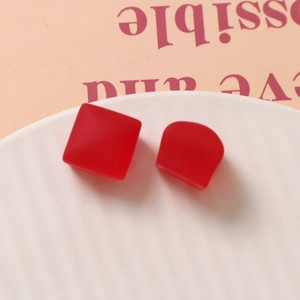 Détails macro de pièces artisanales géométriques en résine rouge sur plat céramique