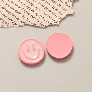 Close-up of pink resin smiley face charms showing both glossy front and flat back details