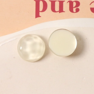 Macro shot of 16mm milk white resin geometric charms with hammered and smooth surface