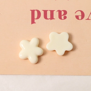Nahaufnahme von zwei cremeweißen Blumenanhängern aus Harz für DIY Haarschmuck