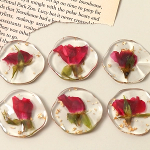 Détail de six breloques en résine avec de vraies roses séchées rouges et des feuilles d'or