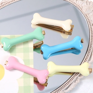 Close-up of colorful resin bone hair clips with golden metal duckbill clips on a vintage mirror