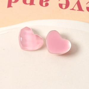 Macro shot of translucent pink resin heart charms for jewelry making in a white tray