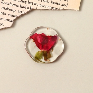 Vue macro d'une breloque en résine avec vraie rose rouge et flocons de feuilles d'or
