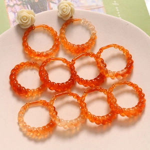 Detailed macro view of orange amber resin earrings with twisted hollow geometric rings