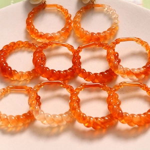 Macro detail of orange amber geometric resin rings with twisted spiral texture for DIY