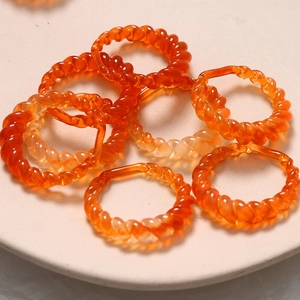 Spiral twisted amber resin rings in geometric hollow design on ceramic tray