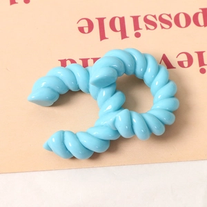 Dettaglio macro di un anello a C a spirale in resina azzurra con trama intrecciata lucida