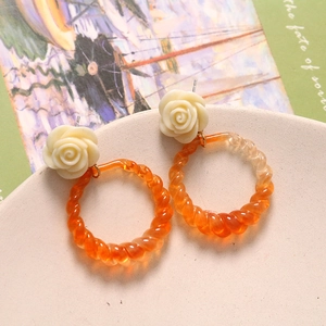 Retro cream rose stud earrings with orange twisted resin rings on elegant backdrop