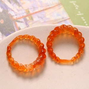 Close-up of amber resin spiral rings on a beige ceramic plate with retro aesthetic