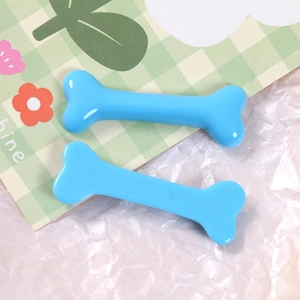 Close-up of shiny blue resin bone hair clips on a decorative green plaid card