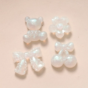 Flat lay of glittery resin bear and flower DIY accessories for crafts on beige surface