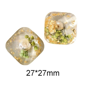 Macro detail of 27x27mm square resin craft parts with gold foil and dried flowers