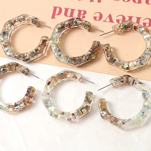 Close-up of C-shaped resin hoop earrings with colorful inlaid crushed shells and stones