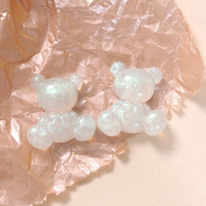 Macro detail of two white glitter resin bears with iridescent sequins for DIY crafts