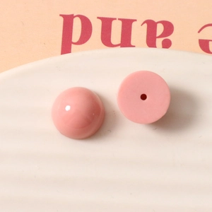 Détail de perles demi-rondes en résine rose avec surface lisse et trou pour bijoux DIY