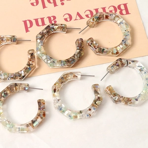 Detail of hexagonal resin earrings with colorful embedded shell fragments and metal posts