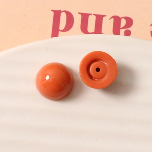 Vue macro d'une perle en résine orange de 12mm avec dos plat et trou central